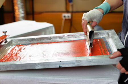 orange ink being pushed through a mesh screen