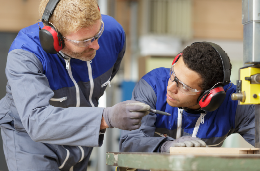 skilled manufacturing laborer training a new employee 
