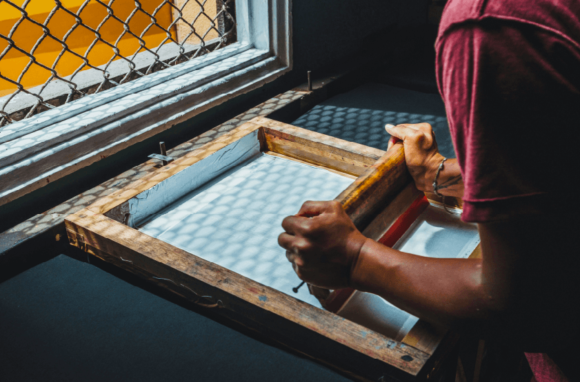 man pushing ink through an exposed screen